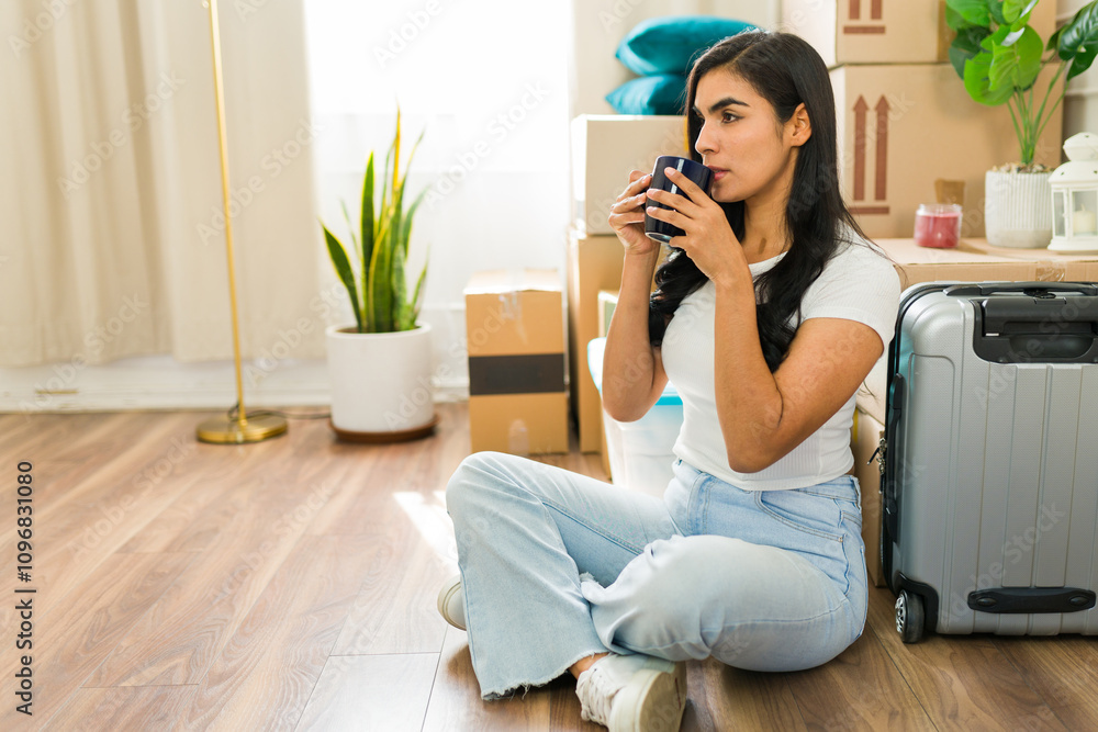 Young woman pauses from unpacking to enjoy a coffee break in her new apartment