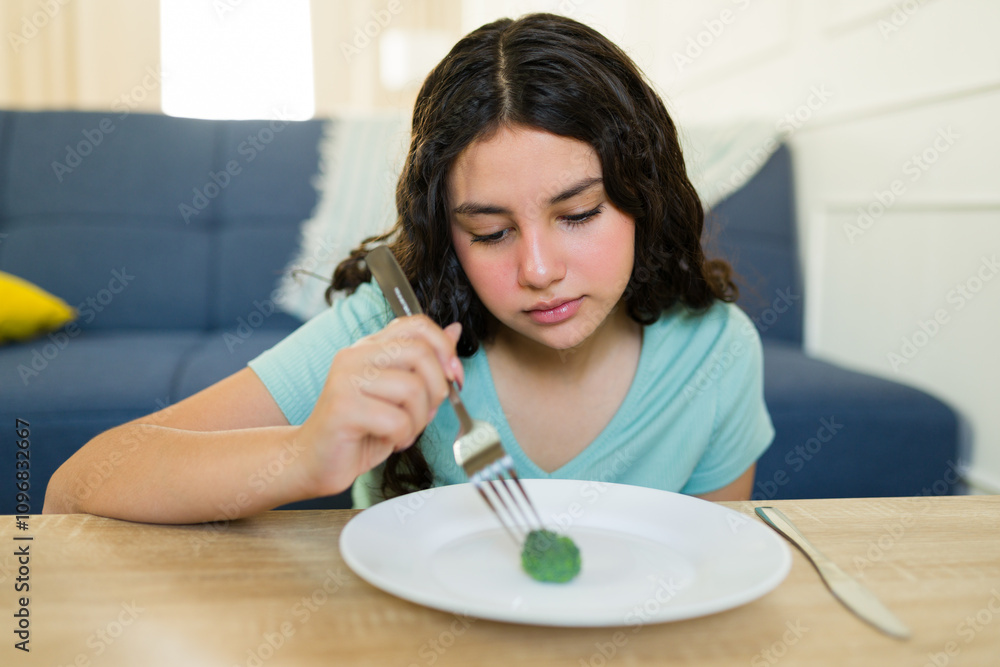 Sad teenage girl staring at a lone broccoli on a plate, struggling with anorexia or bulimia and maintaining a highly limited diet Sad teenage girl staring at a lone broccoli on a plate, struggling with anorexia or bulimia and maintaining a highly limited diet