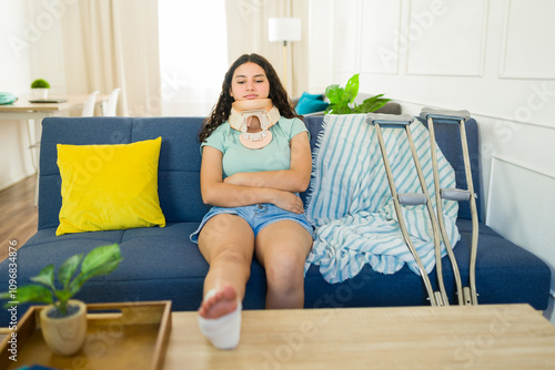 Teenage girl with a neck brace and leg cast resting on the sofa at home as she recuperates from an injury photo