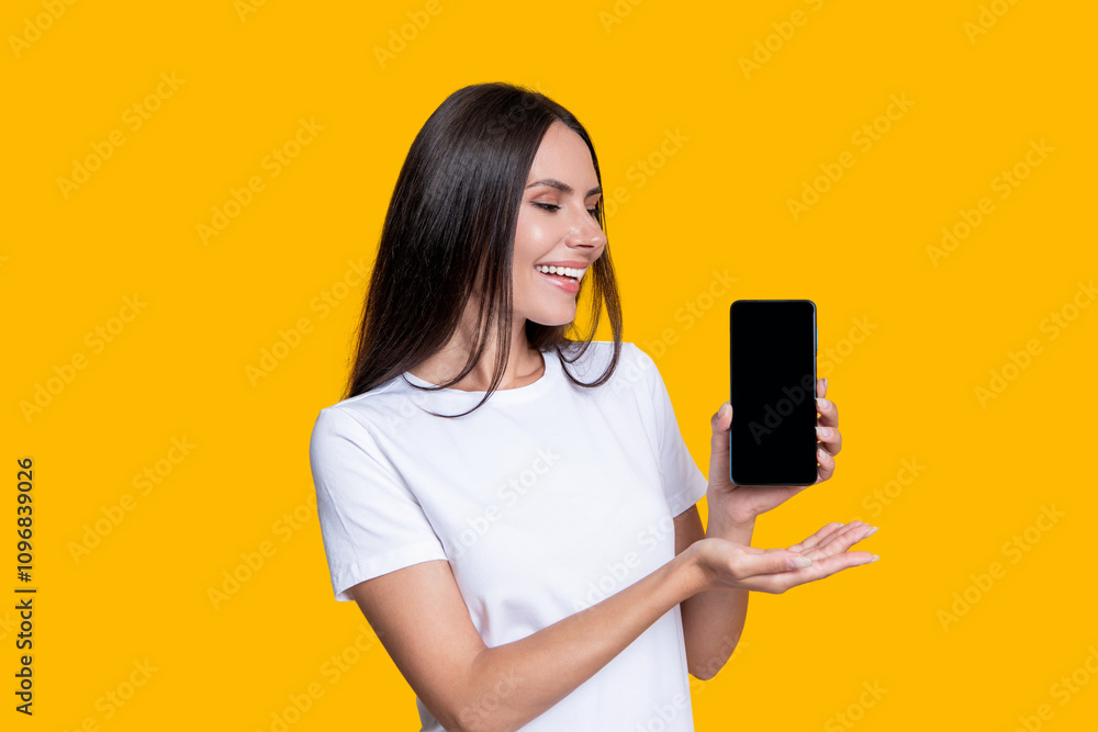 Naklejka premium Woman presenting phone screen. Young girl showing phone isolated on yellow. Millennial woman. New phone app. Girl offer advertisement. Presenting product. Advertisement of business app. Work online