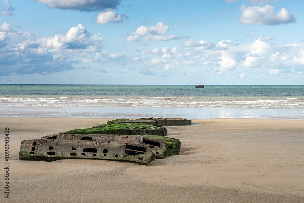 Remains of a World War II Mulberry harbor on a sandy beach at Arromanches, Normandy, France Remains of a World War II Mulberry harbor on a sandy beach at Arromanches, Normandy, France