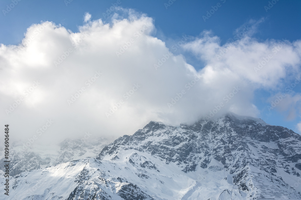 Clouds over mountain summit in the European Alps in winter Clouds over mountain summit in the European Alps in winter