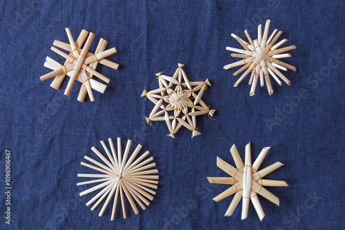 Eine Nahaufnahme von verschiedenen Strohsternen auf der blauen Tischdecke. Draufsicht. Weihnachtlicher Hintergrund.