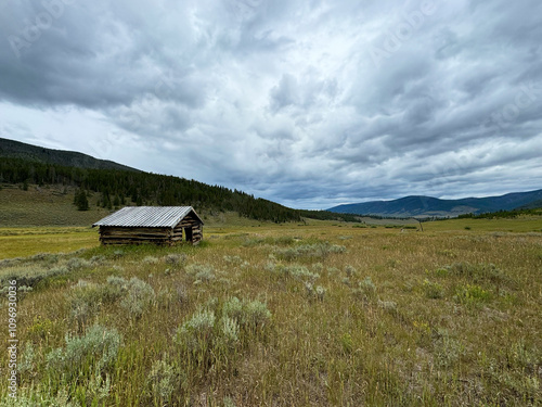 Old cabin in a meadow in the mountains with clouds in soda park Colorado