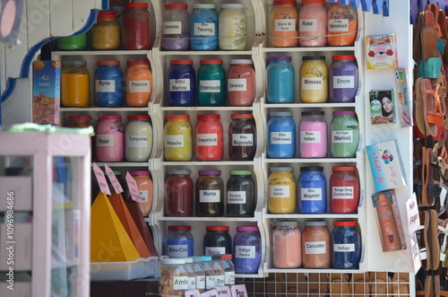 Wallpaper Mural Display of vibrant pigments in glass jars at a shop in Essaouira, showcasing a wide range of traditional colors used in Moroccan art and crafts, adding a splash of color to the market scene
 Torontodigital.ca