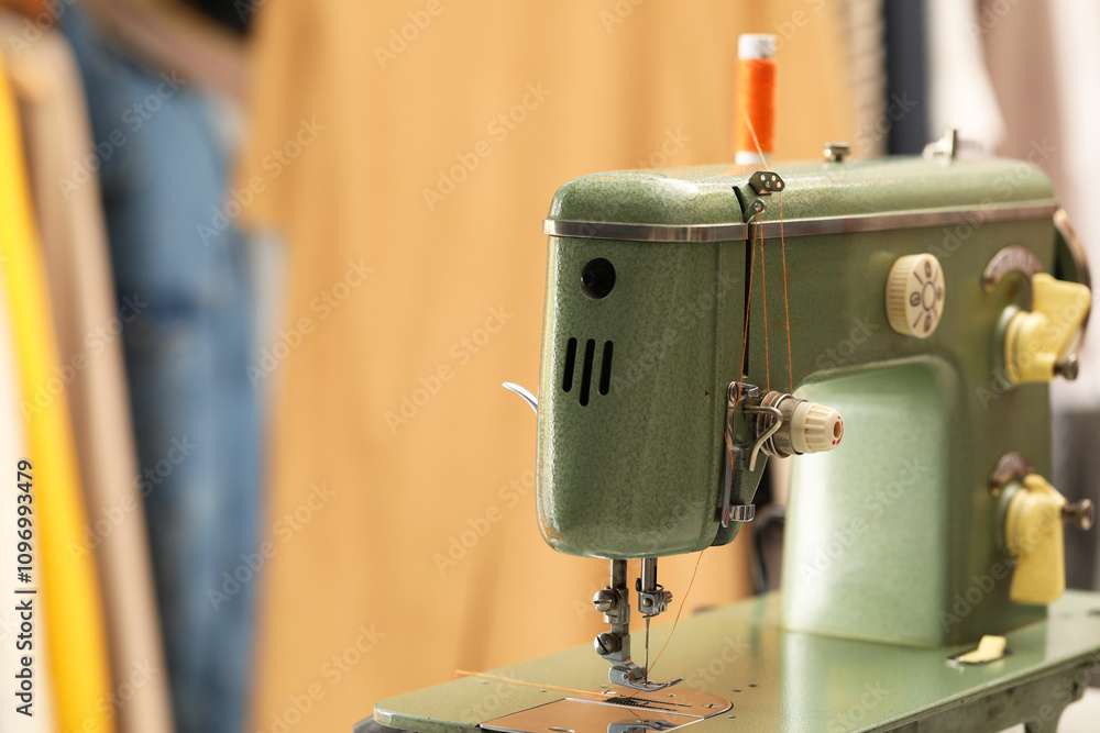 Fototapeta premium Vintage sewing machine with thread on blurred background, closeup. Space for text