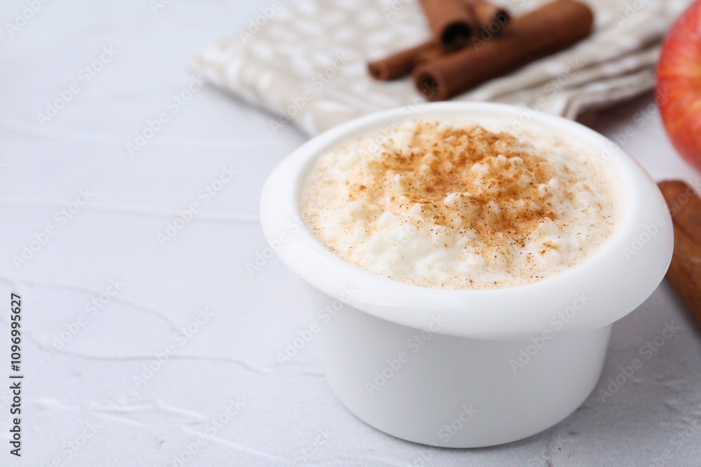 Delicious rice pudding with cinnamon on white textured table, closeup. Space for text Delicious rice pudding with cinnamon on white textured table, closeup. Space for text