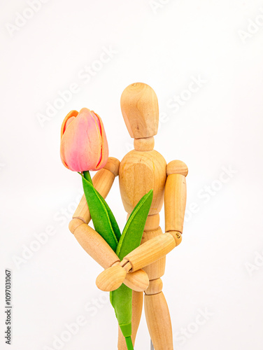 Wooden man holding one pink tulip, holiday greeting photo