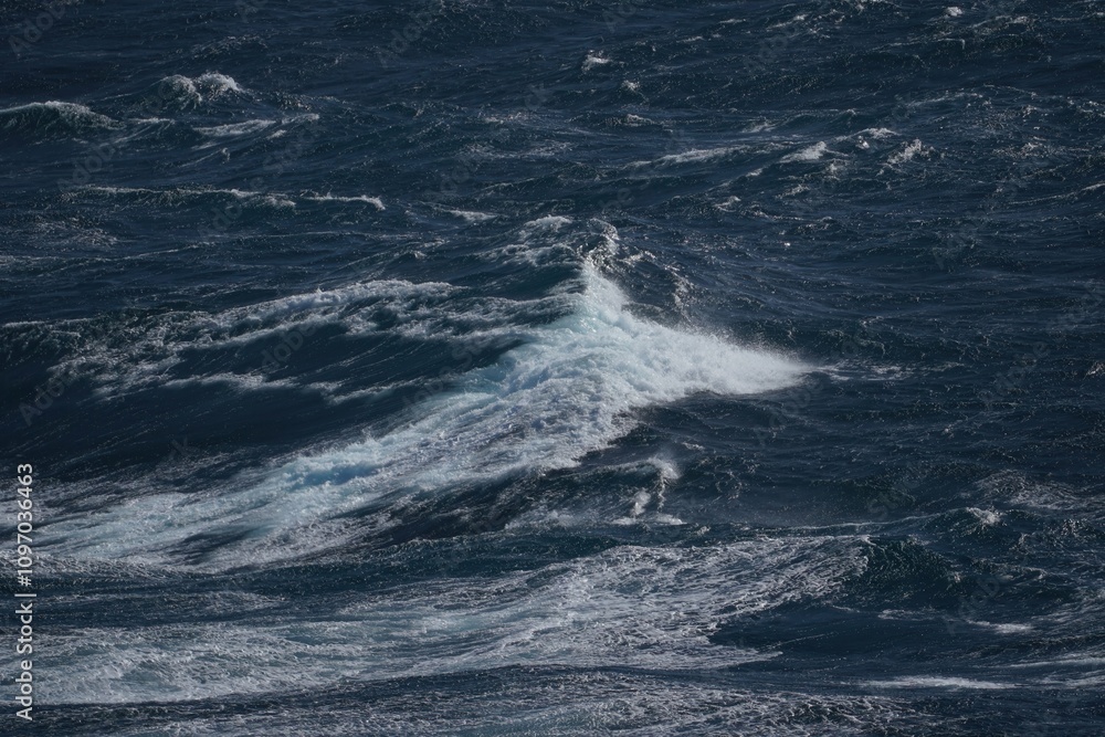 Rough ocean waves crashing in deep blue water create dramatic scene. powerful movement of sea evokes sense of nature strength and beauty Rough ocean waves crashing in deep blue water create dramatic scene. powerful movement of sea evokes sense of nature strength and beauty