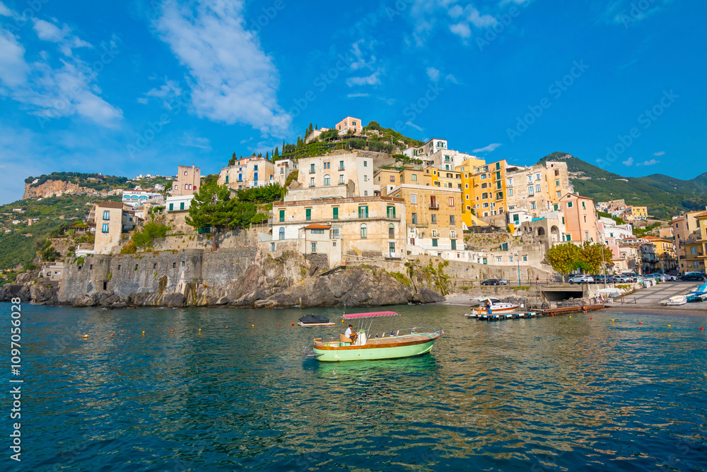 Fototapeta premium This image showcases Minori on the Amalfi Coast, with its charming seaside houses, tranquil beach, and lush green hills, bathed in the warm Mediterranean light.
