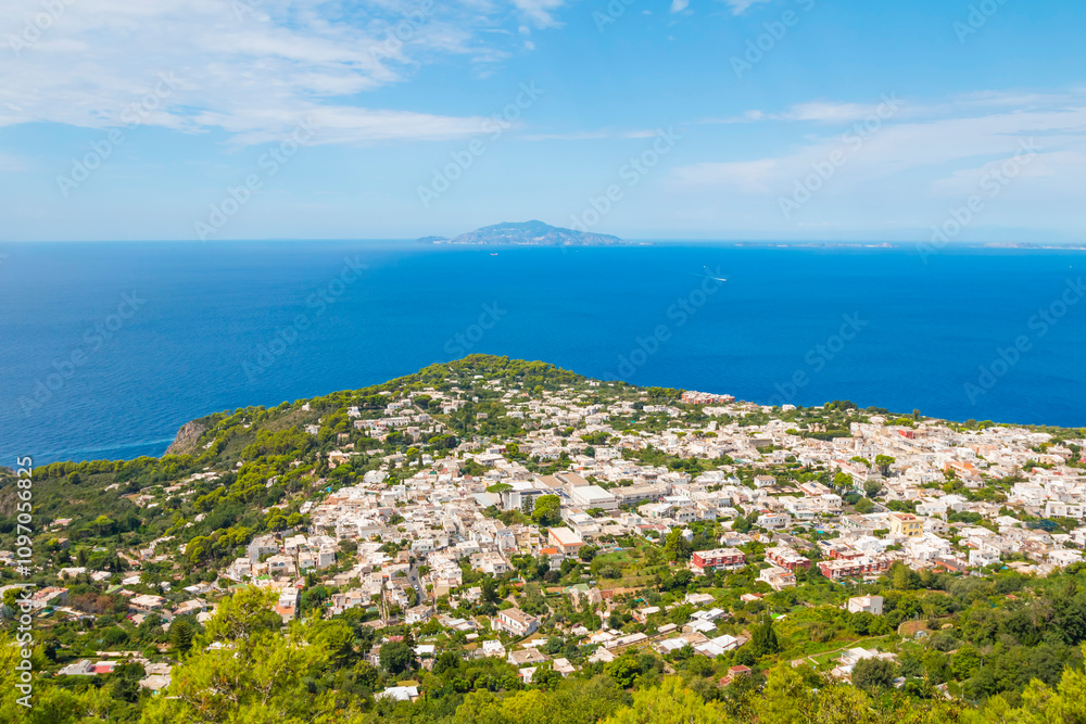 Obraz premium The photo offers a scenic view from the cable car to Anacapri, Italy, showcasing sweeping landscapes, vibrant greenery, and the azure sea, capturing the beauty of this stunning island route.