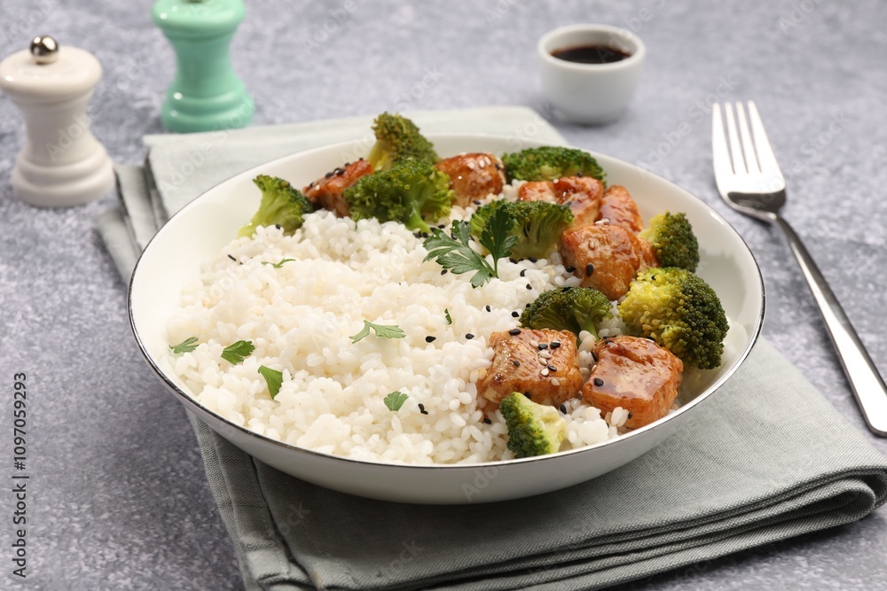 Tasty rice with broccoli and chicken served on grey table, closeup Tasty rice with broccoli and chicken served on grey table, closeup