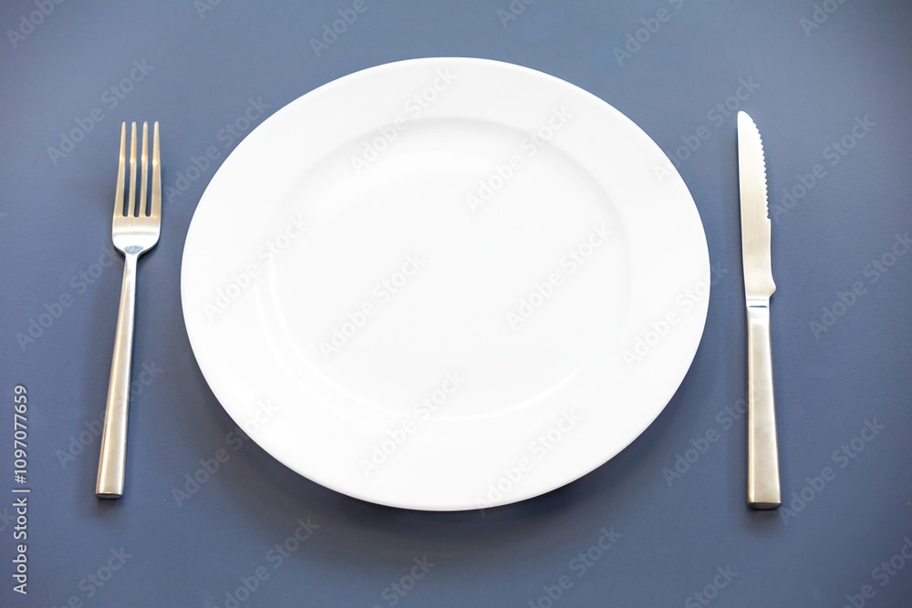 Empty plate top view with metal cutlery next to it Empty plate top view with metal cutlery next to it