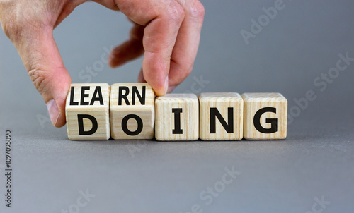 Doing or learning symbol. Businessman turns wooden cubes and changes the word Doing to Learning . Beautiful grey table grey background. Educational business doing or learning concept. Copy space.
