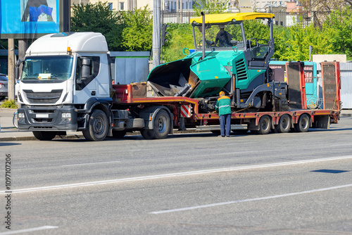Obraz na płótnie Heavy machinery transportation on a bustling city street in broad daylight. Copy space. w salonie
