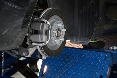 Close-up of a car brake system on a maintenance lift in an auto repair shop.