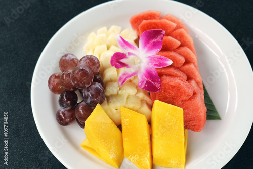 A vibrant assortment of fresh fruits displayed artistically on a white plate.
