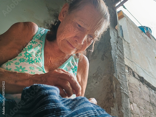 Beautiful portrait of a Latin grandmother sewing clothes inside her house in Neiva - Huila - Colombia. Concept of senior citizen and work photo