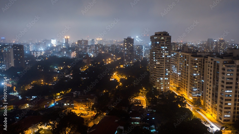 Fototapeta premium Night cityscape with illuminated residential buildings and park area in misty weather. Aerial view of modern urban district with glowing streets and high-rise apartments. City lights in fog