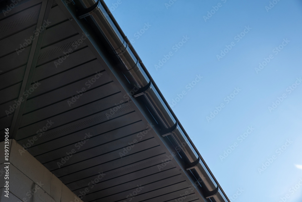 Metal soffit and gutter installation highlighting sleek design against a clear blue sky Metal soffit and gutter installation highlighting sleek design against a clear blue sky