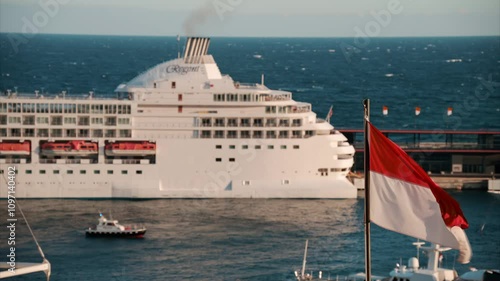 The flag of Monaco waving with a ship moving on the sea on the background photo