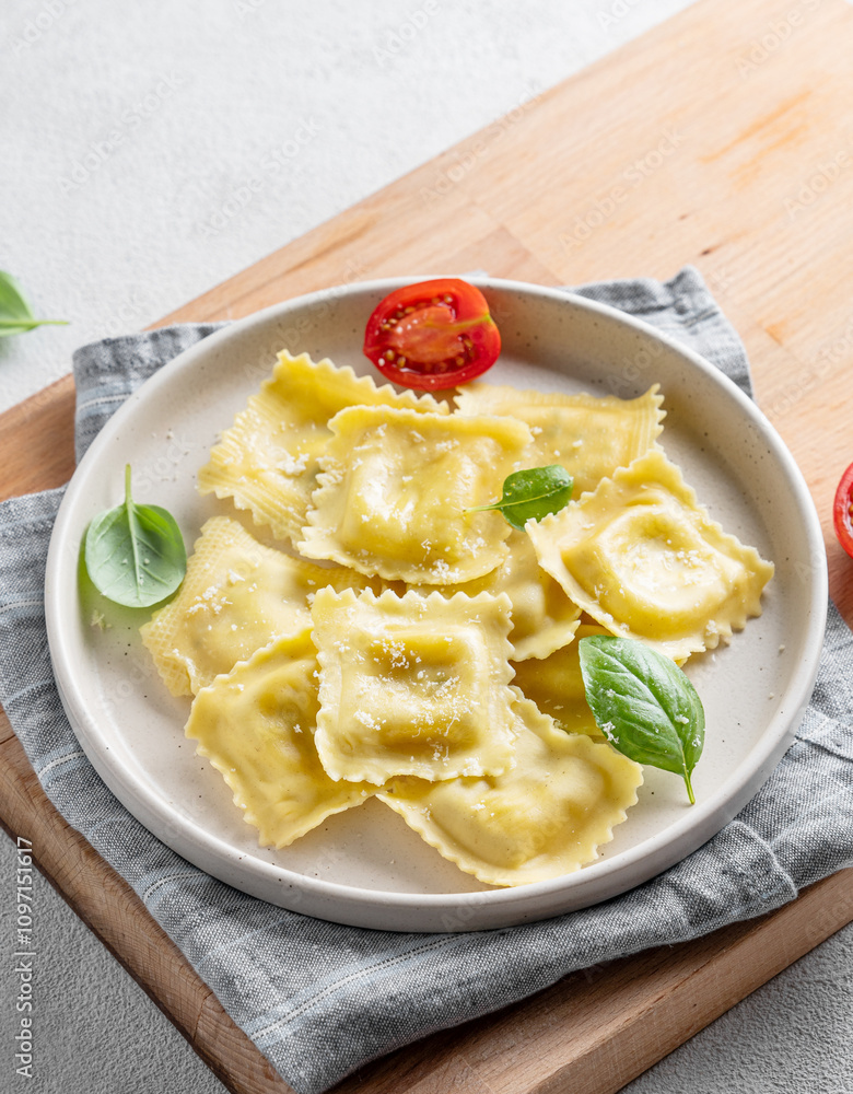 Homemade ravioli pasta with cheese, tomatoes and basil in a plate on a cutting board on a light background Homemade ravioli pasta with cheese, tomatoes and basil in a plate on a cutting board on a light background