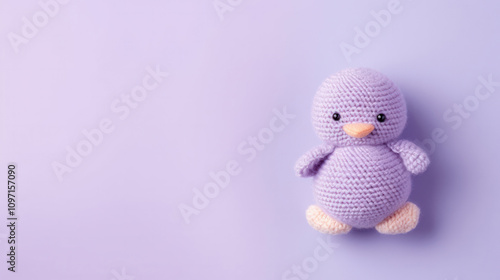 Purple crocheted bird with orange beak and feet on a pastel lilac background, showcasing intricate handmade craftsmanship and cheerful simplicity under soft lighting... photo