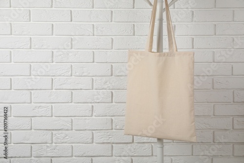 Eco bag hanging on clothing rack near white brick wall. Mockup for design photo