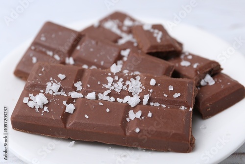 Pieces of chocolate with salt on white table, closeup