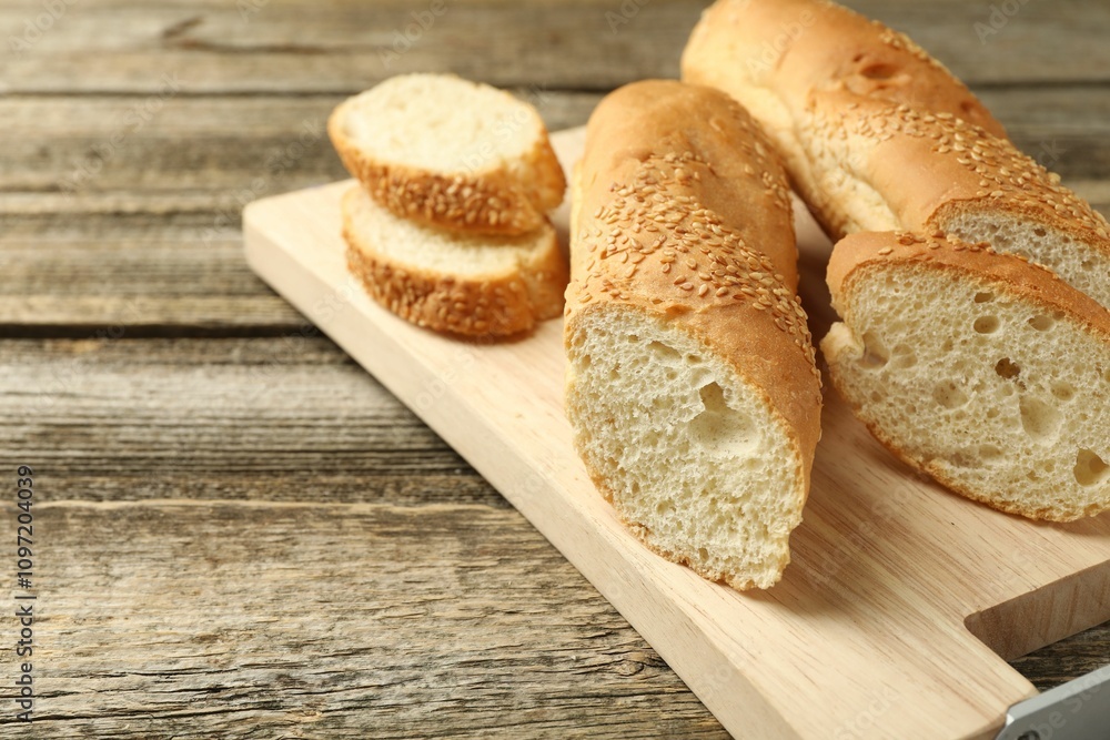 Cut fresh baguette with sesame on wooden table, closeup. Space for text Cut fresh baguette with sesame on wooden table, closeup. Space for text