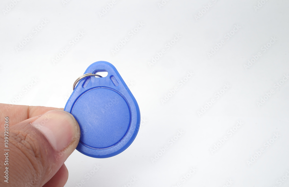 Fototapeta premium A blue RFID (Radio Frequency Identification) keychain receiver is held in a hand on a white background. Used by electronics, mechatronics, and networking engineers.