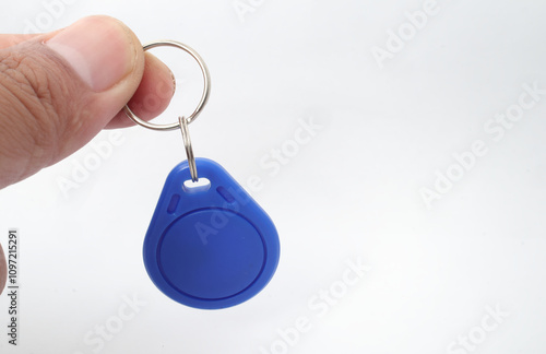 A blue RFID (Radio Frequency Identification) keychain receiver is held in a hand on a white background. Used by electronics, mechatronics, and networking engineers. photo