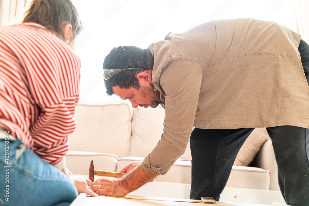 Happy Couple Assembles Furniture as a Team, Girl Reads Instructions and Boy Tightens Screw with a Drill. Moving into New Apartment, Couple Assemble Shelf. Happy Couple Assembles Furniture as a Team, Girl Reads Instructions and Boy Tightens Screw with a Drill. Moving into New Apartment, Couple Assemble Shelf.