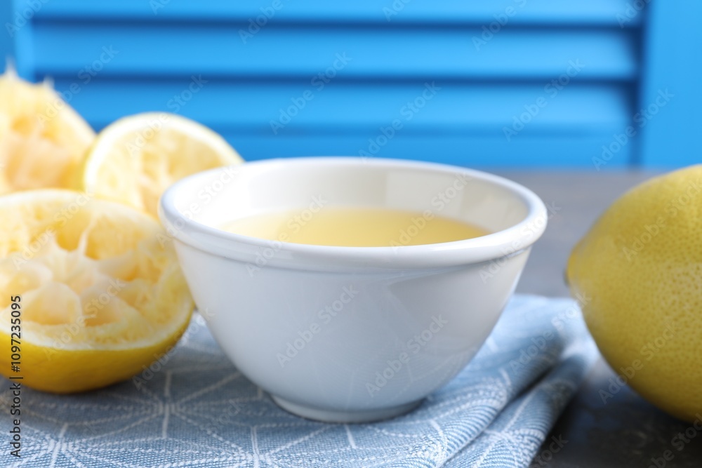 Fresh lemon juice in bowl and fruits on table, closeup Fresh lemon juice in bowl and fruits on table, closeup