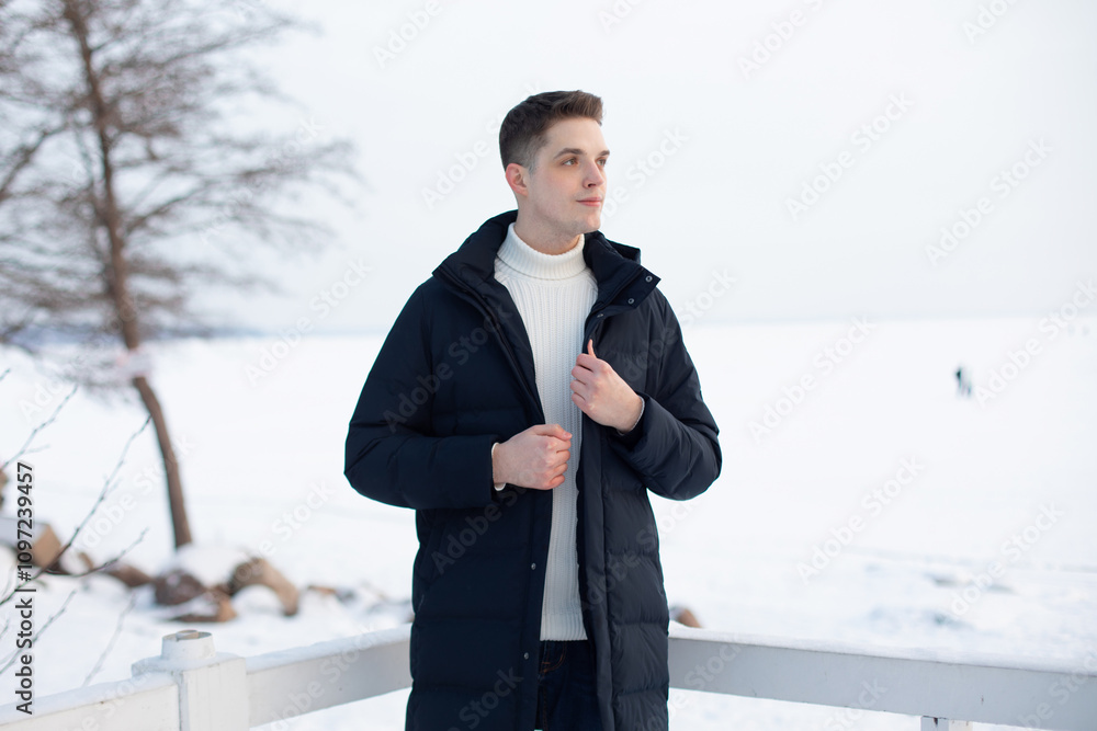 Portrait of young handsome man in sweater and coat in winter park Portrait of young handsome man in sweater and coat in winter park