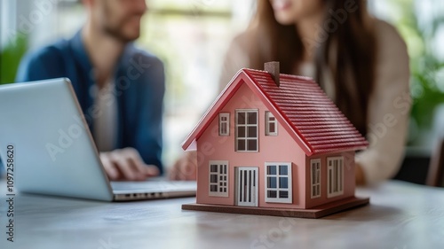 Couple discussing mortgage options with laptop and model house on table