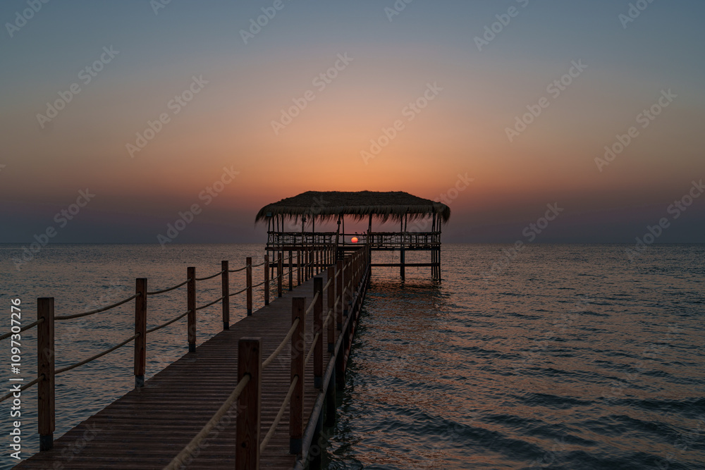 A beautiful view of the sunrise, sunset over the sea horizon with a pier in the foreground A beautiful view of the sunrise, sunset over the sea horizon with a pier in the foreground