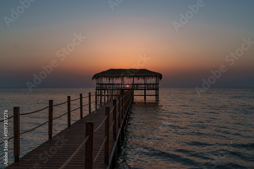 A beautiful view of the sunrise, sunset over the sea horizon with a pier in the foreground