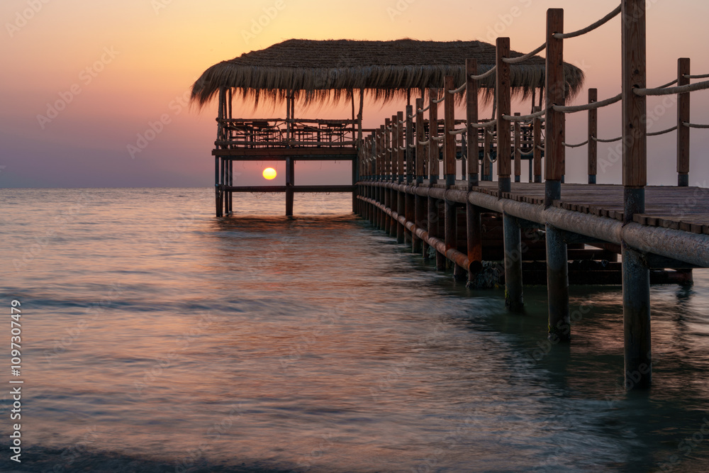 A beautiful view of the sunrise, sunset over the sea horizon with a pier in the foreground A beautiful view of the sunrise, sunset over the sea horizon with a pier in the foreground