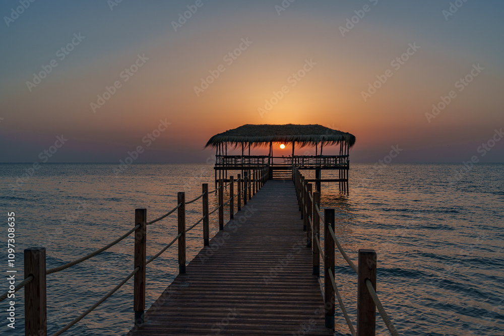 A beautiful view of the sunrise, sunset over the sea horizon with a pier in the foreground A beautiful view of the sunrise, sunset over the sea horizon with a pier in the foreground