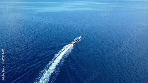 Wooden boat drifting across vibrant blue ocean waters. Aerial footage