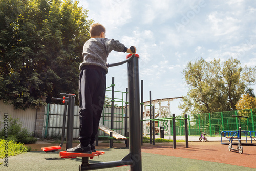 Young Boy Exercising on Outdoor Stepper Equipment in Public Playground During Daytime Physical Activity and Fitness Training