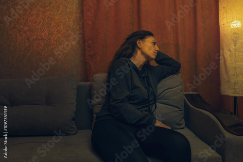 Depressed Woman Sitting Alone in Dark Room Showing Signs of Mental Health Crisis and Emotional Distress in Home Environment