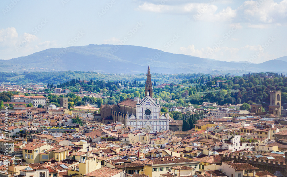 Obraz premium A bird's-eye view of Florence, italy reveals a breathtaking panorama of the city's iconic red-tiled rooftops, the majestic Duomo, and the Arno River, all framed by the rolling Tuscan hills.