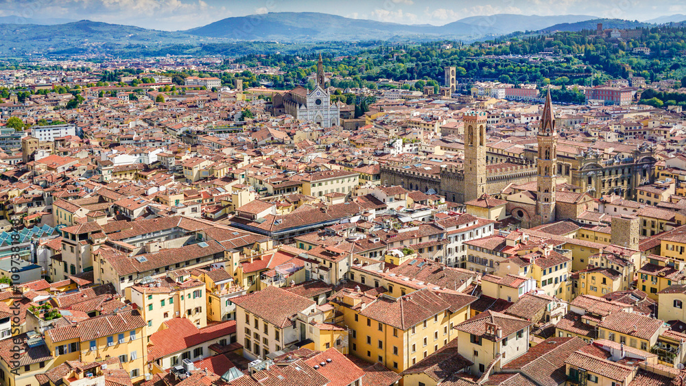 Fototapeta premium A bird's-eye view of Florence, italy reveals a breathtaking panorama of the city's iconic red-tiled rooftops, the majestic Duomo, and the Arno River, all framed by the rolling Tuscan hills.