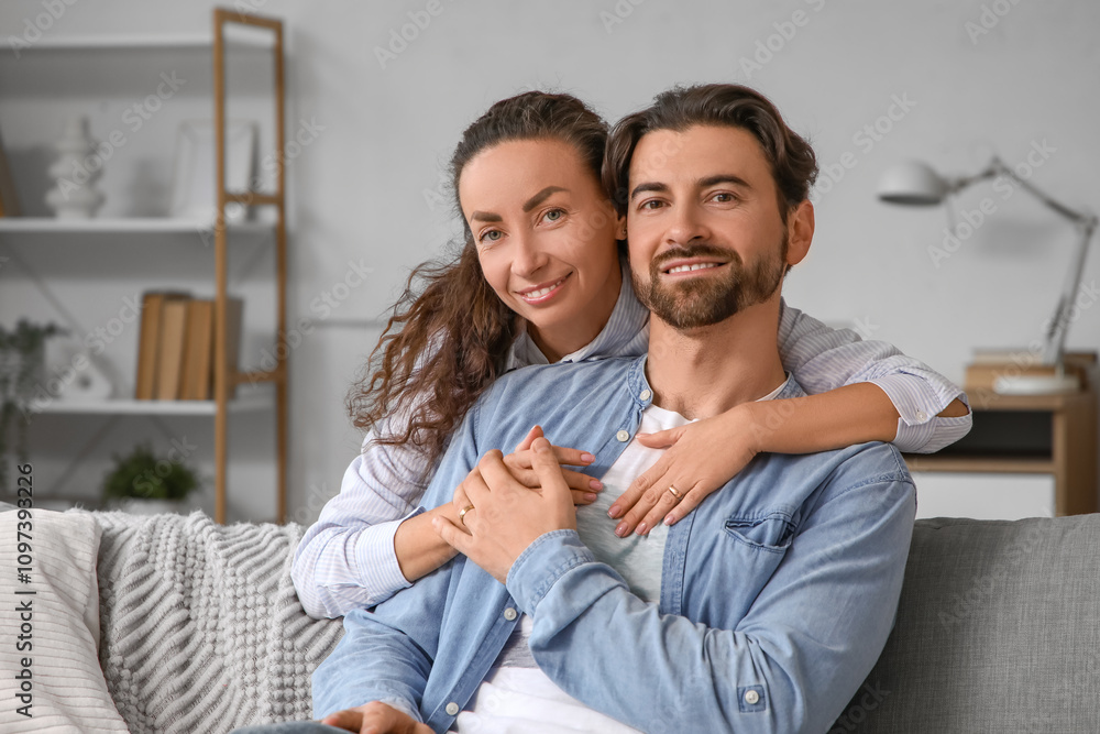 Happy wife hugging her husband on sofa at home Happy wife hugging her husband on sofa at home