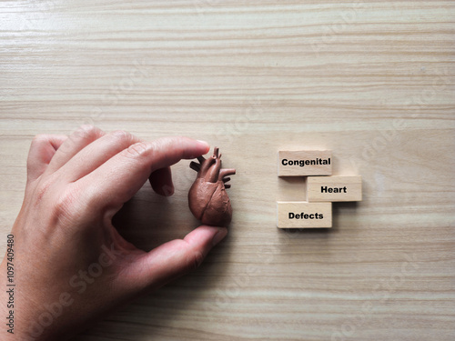 A miniature heart is placed beside three wooden blocks spelling 