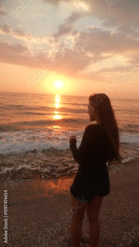A captivating silhouette of a woman standing gracefully at sunset on the tranquil beach
