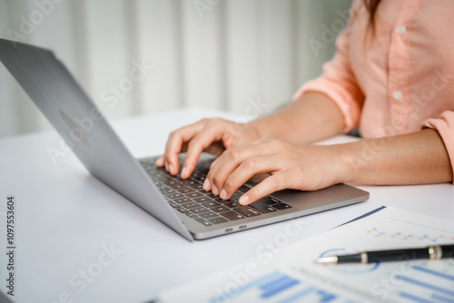 A close-up of a businesswoman working on a laptop in an office. As an accountant, she records financial data, verifies documents, manages income and expenses, ensuring accurate financial reporting