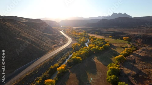 This breathtaking aerial shot captures the mesmerizing beauty of Zion National Park, showcasing vibrant fall foliage and impressive rock formations bathed in the stunning light of sunset in Utah